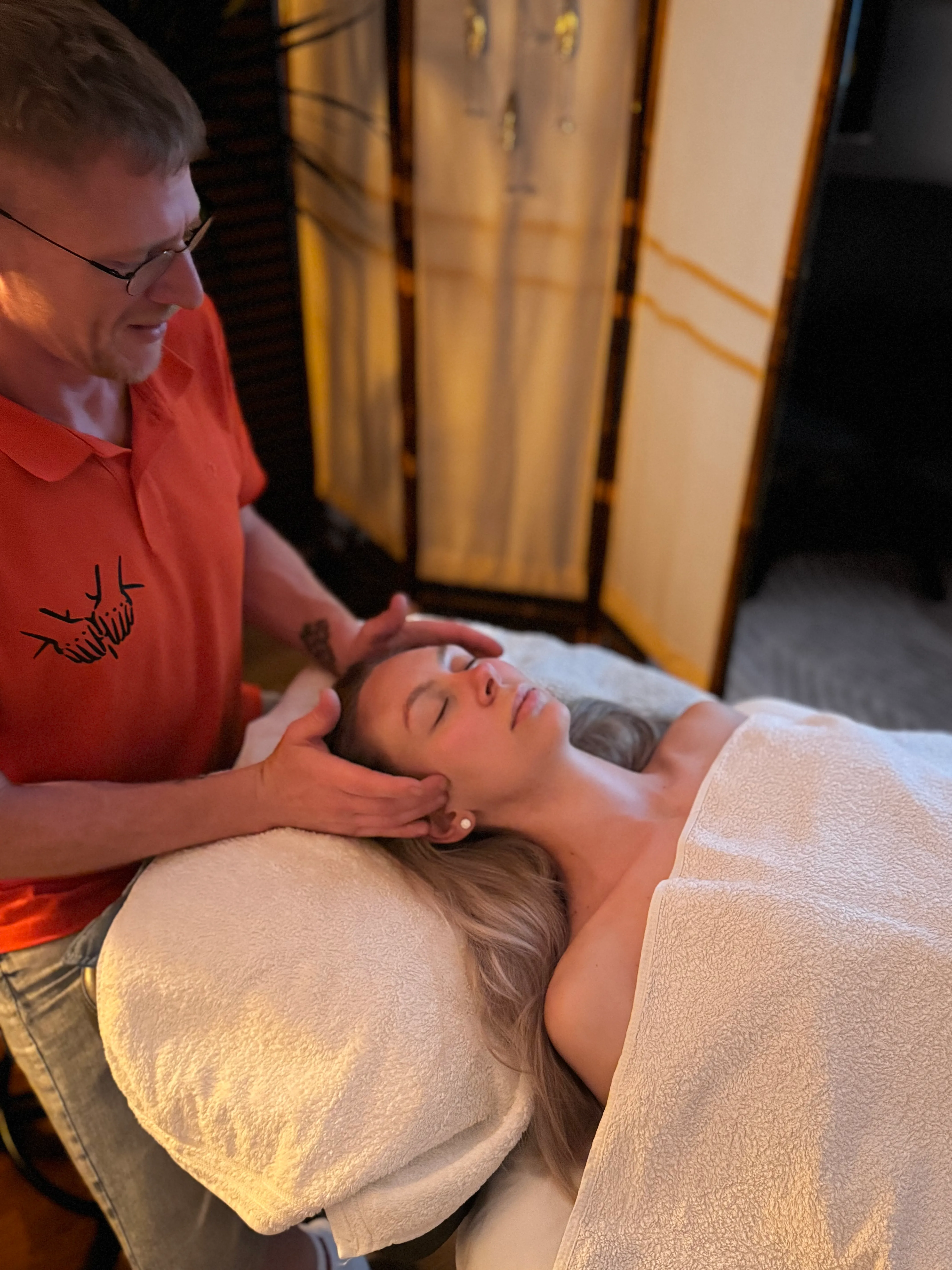 Heilmasseur führt eine sanfte Lymphdrainage im Kopf- und Gesichtsbereich durch